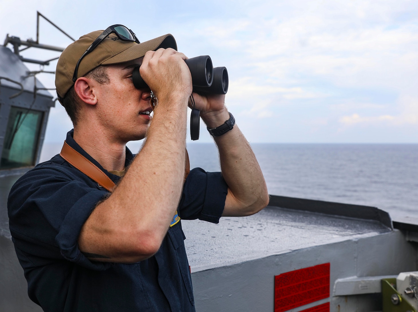 210712-N-FO714-1033 SOUTH CHINA SEA (July 12, 2021) Lt.j.g. Andrew Hayne, from Parker, Colo., uses binoculars to monitor a surface contact from the bridge wing of the Arleigh Burke-class guided-missile destroyer USS Benfold (DDG 65) while conducting routine underway operations. Benfold is forward-deployed to the U.S. 7th Fleet area of operations in support of a free and open Indo-Pacific. (U.S. Navy photo by Mass Communication Specialist 1st Class Deanna C. Gonzales)