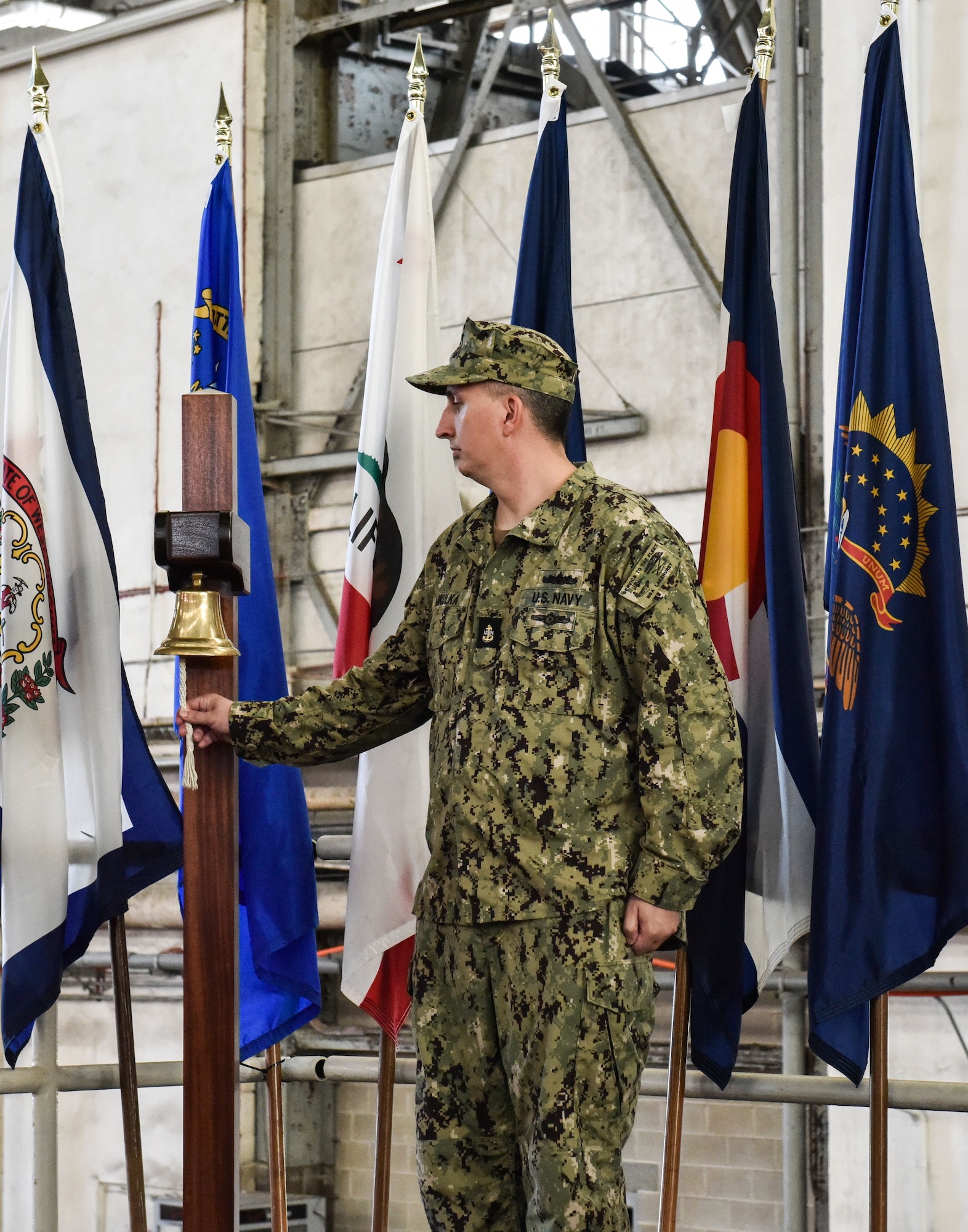 A U.S. Navy Sailor strikes a bell to announce the arrival of the official party during the Naval Air Engineer Station Lakehurst change of command ceremony at Joint Base McGuire-Dix-Lakehurst, New Jersey, July 8, 2021. U.S. Navy Capt. William R. Sherrod relinquished command of NSA Lakehurst to Capt. Frank T. Ingargiola inside historic Hangar 1. (U.S. Air Force Photo by Staff Sgt. Shay Stuart)