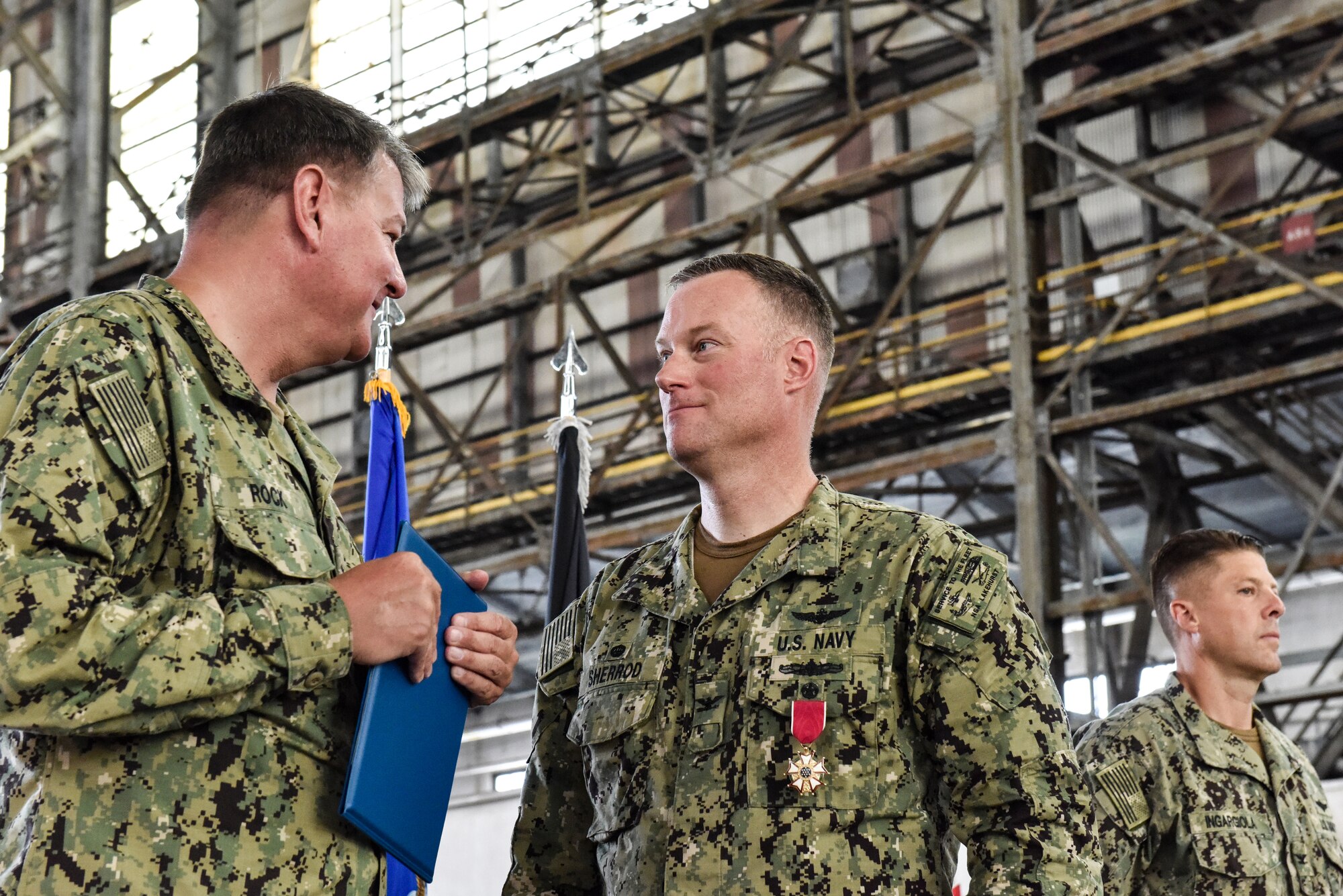 U.S. Navy Rear Adm. Charles Rock presents outgoing commander U.S. Navy Capt. William R. Sherrod with the Legion of Merit during Sherrod’s change of command ceremony at Joint Base McGuire-Dix-Lakehurst, New Jersey, July 8, 2021. Sherrod was awarded for his exceptionally meritorious conduct in the performance of outstanding service as Commanding Officer. (U.S. Air Force Photo by Staff Sgt. Shay Stuart)