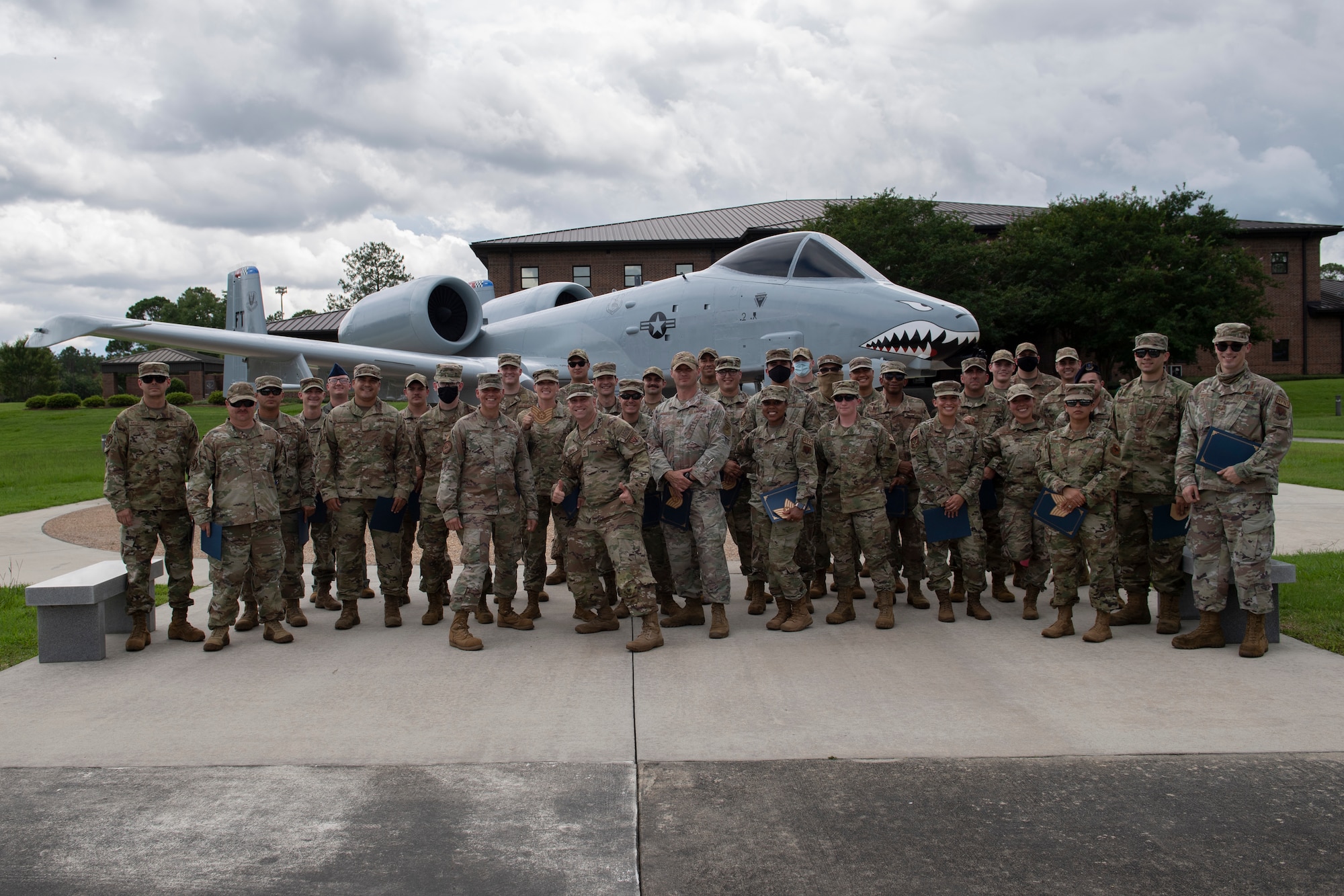 A photo of a group of 40 people standing in front on an A-10C Thunderbolt II aircraft.