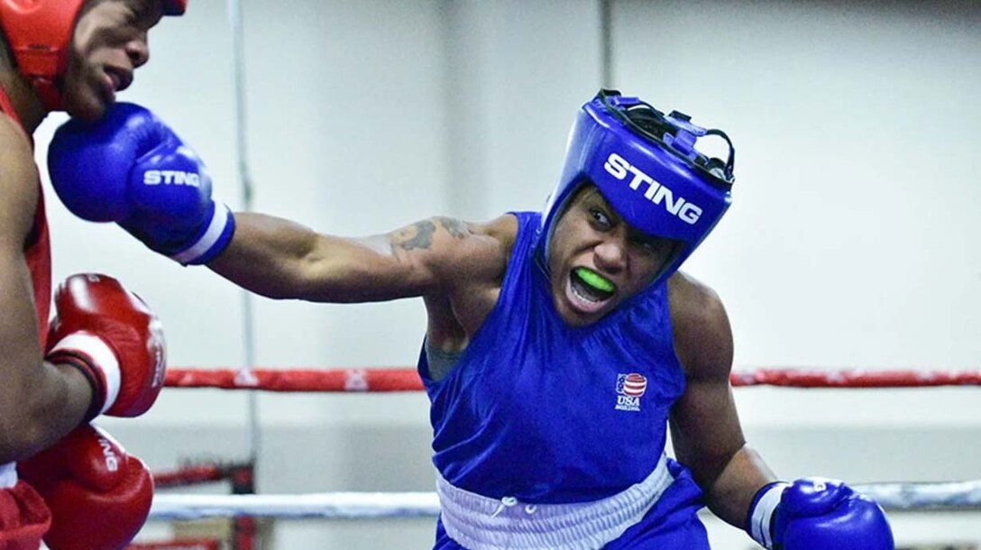 A boxer throws a punch at another boxer in a boxing ring.