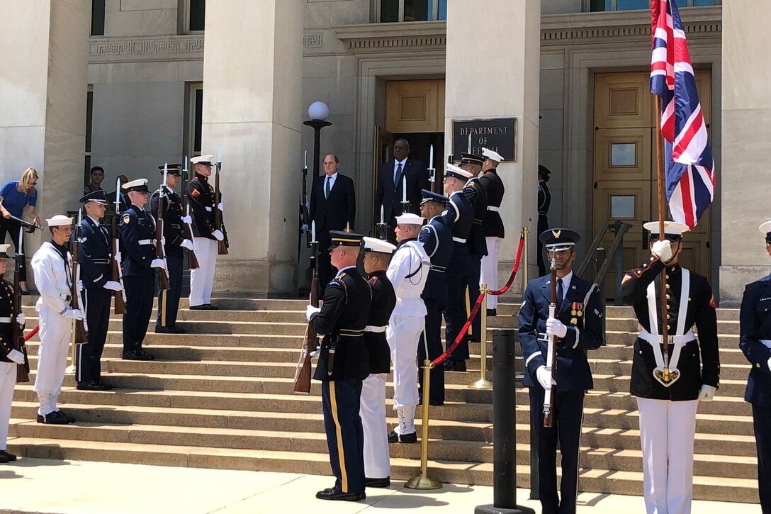 Two men stand after passing through a joint service honor guard.