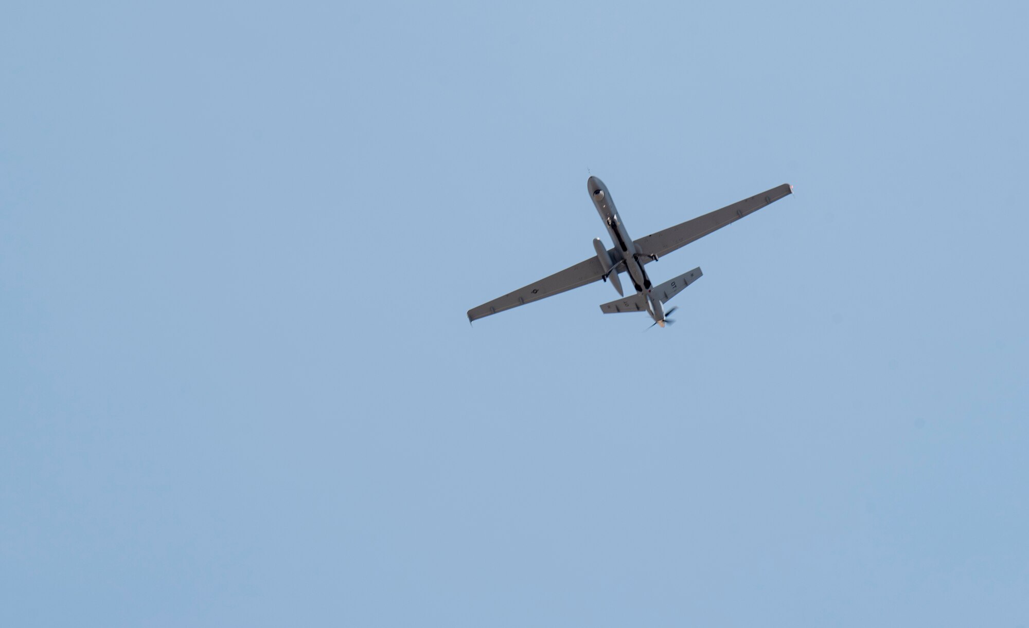An MQ-9 Reaper flies through a clear blue sky over Holloman AFB, New Mexico.