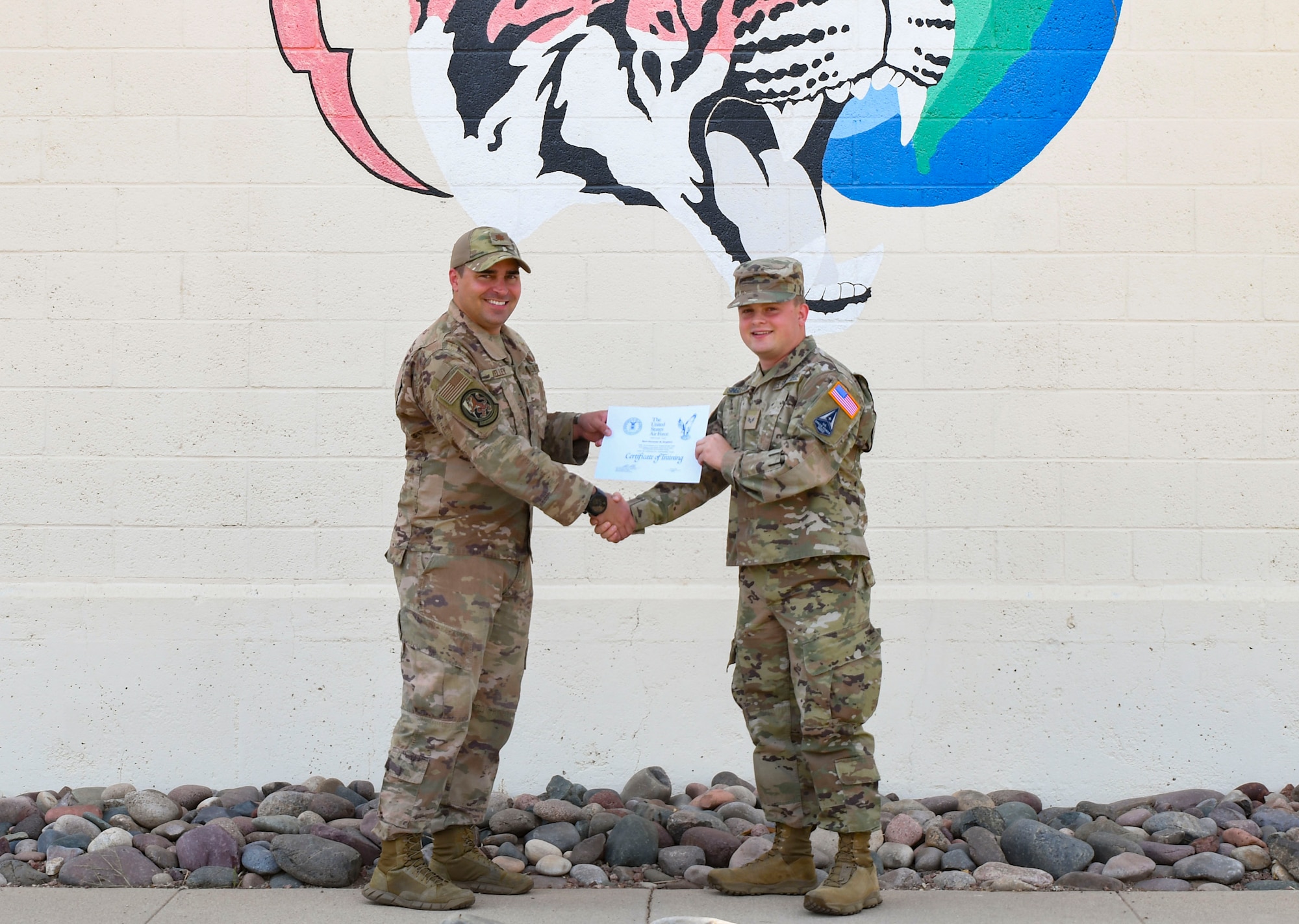 A photo of an airman handing another airman a certificate