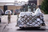 Airman walks beside pallet of supplies