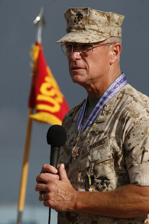 A Marine speaks with a flag next to him.