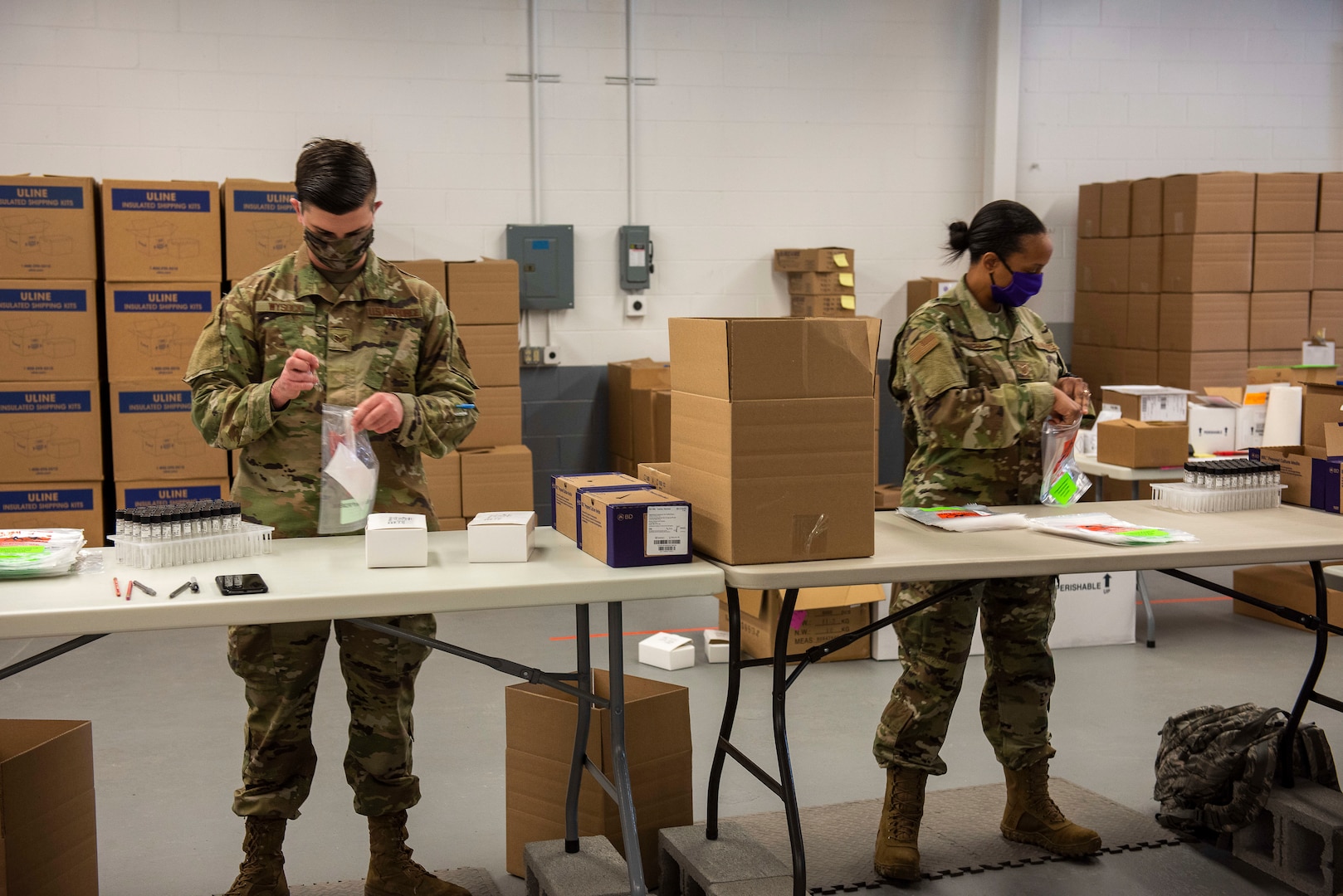 From left, U.S. Air Force Senior Airmen Lucas Wysock and Technical Sgt. Christina McGill, 158th Fighter Wing, Vermont Air National Guard, assemble COVID-19 test kits at the Strategic National Stockpile Warehouse, August 27, 2020. Airmen from across the 158th Fighter Wing have supported operations at the SNS Warehouse since March 2020, and continue to provide critical logistical support to enable Vermont's efforts to distribute Personal Protective Equipment throughout the state and conduct widespread testing for COVID-19. (U.S. Army National Guard photo by Capt. J. Scott Detweiler)
