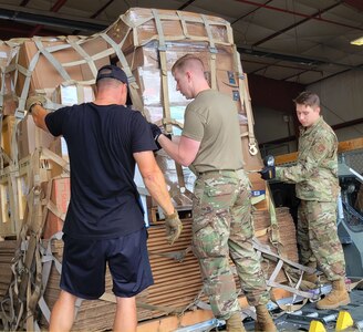 Daniel Guthrie, Polar Field Services cargo supervisor, works with Senior Airman Ian Chisholm, left, and Airman 1st Class Trevor Cornelius to secure a pallet of cargo at Stratton Air National Guard Base, Scotia, N.Y.  The Air Force Reserve Airmen from the 87th Aerial Port Squadron are being trained by air transportation specialists assigned to the 109th Airlift Wing.