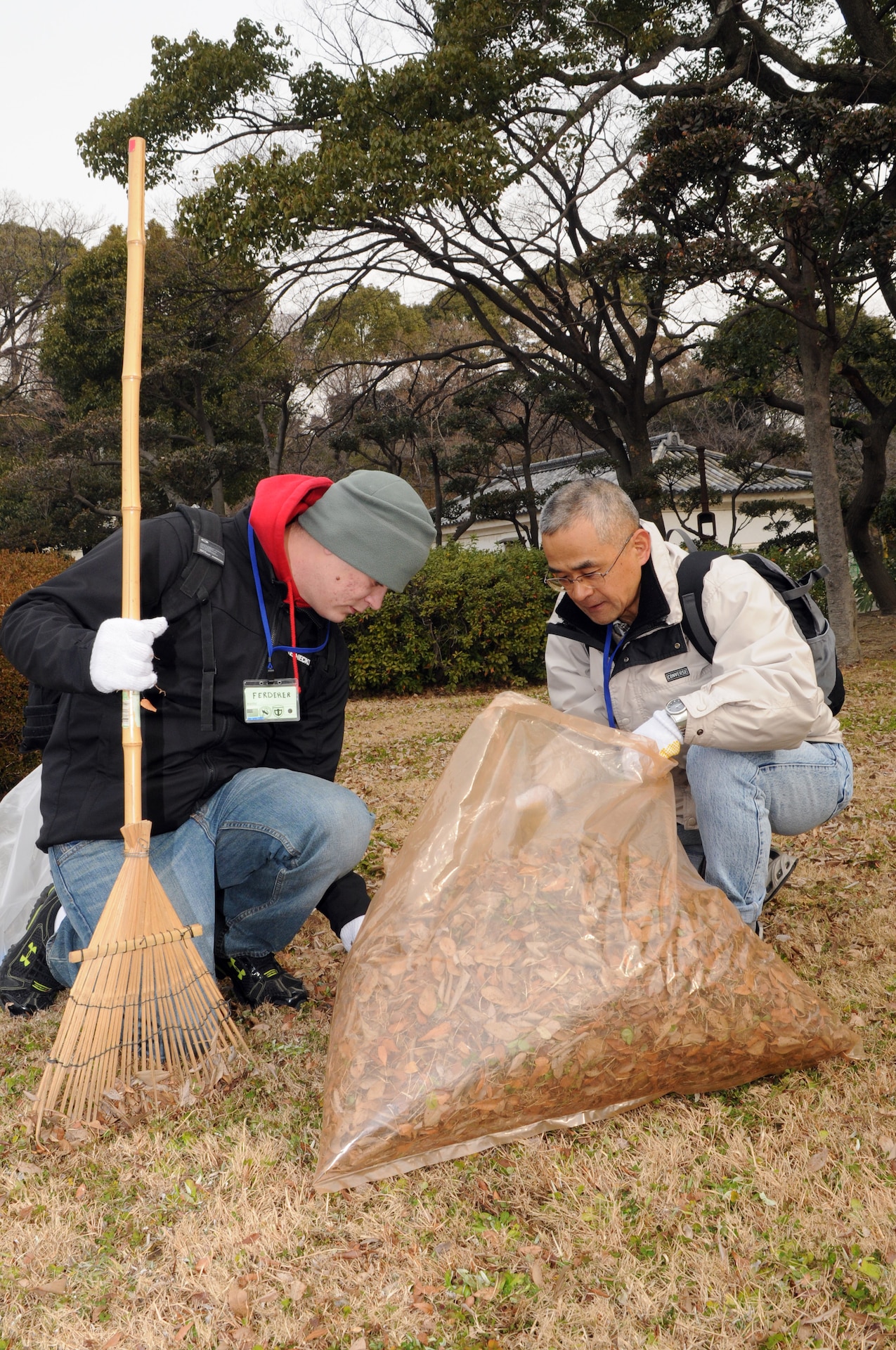 Spc. Isaac J. Ferderer, battle radio transmitter operator for the 34th Infantry Division, Minnesota National Guard, assists a member of the Japan Ground Self-Defense Force during a cleanup of Osaka Castle in Osaka, Japan Jan. 28.