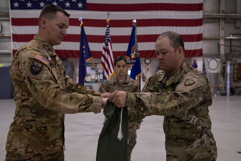 Maj. Daniel Klinkner, left, and Staff Sgt. Cidjomor Fischer furl the company colors during the 2nd Battalion, 641st Aviation Regiment casing ceremony at the unit's aircraft hangar on Joint Base Elmendorf-Richardson, July 9, 2021. The traditional casing ceremony was held as the unit prepares to leave for the mobilization station at Fort Bliss, Texas, prior to deployment overseas. (U.S. Army National Guard photo by Victoria Granado)
