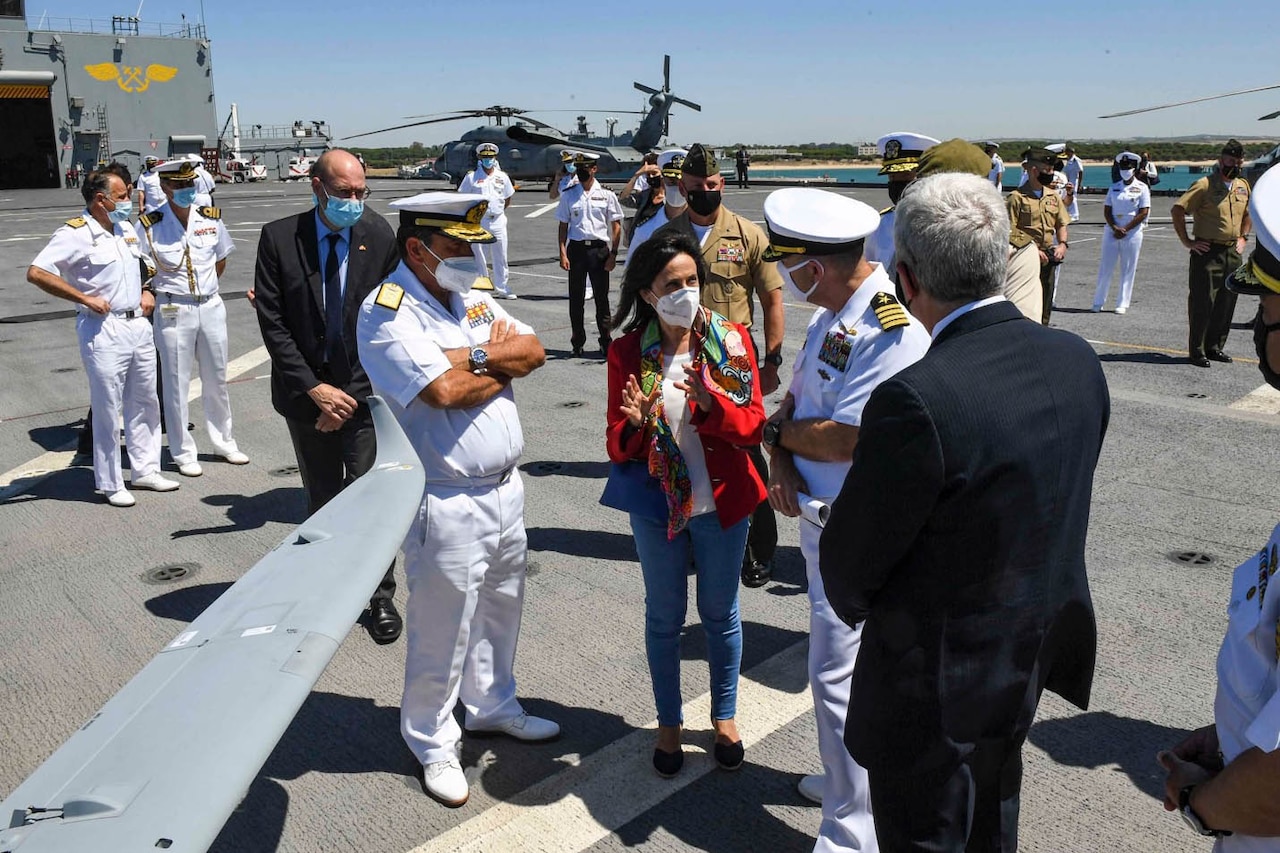 A woman in civilian clothing speaks with military officials.