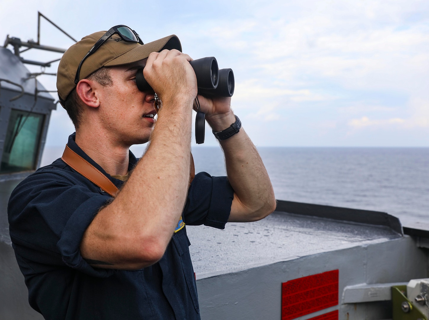 SOUTH CHINA SEA (July 12, 2021) Lt.j.g. Andrew Hayne, from Parker, Colo., uses binoculars to monitor a surface contact from the bridge wing of the Arleigh Burke-class guided-missile destroyer USS Benfold (DDG 65) while conducting routine underway operations. Benfold is forward-deployed to the U.S. 7th Fleet