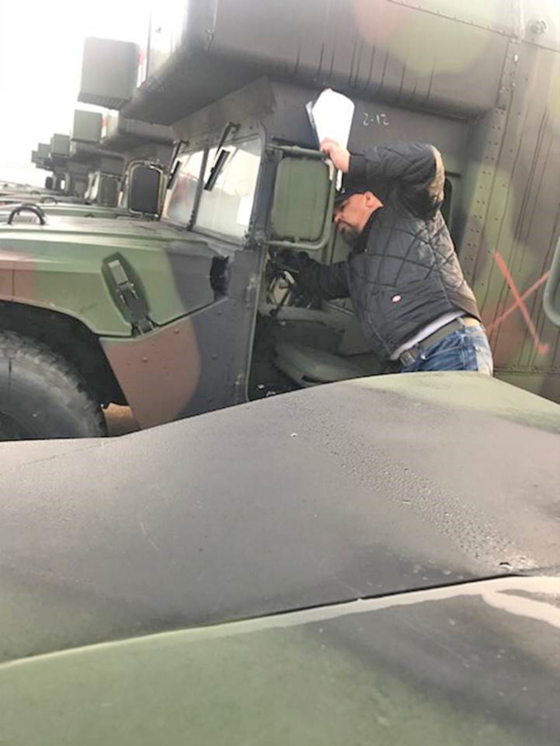 Man looks inside a camo painted vehicle