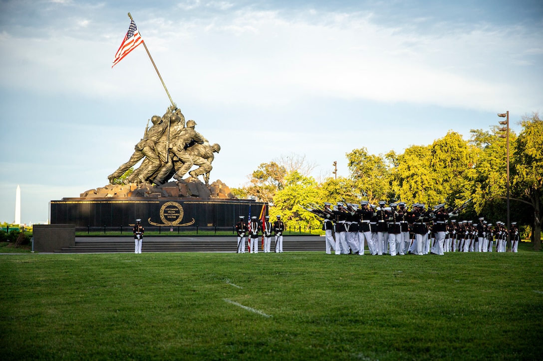 Marines with the Silent Drill Platoon execute their “bursting bomb” sequence during the Tuesday Sunset Parade at the Marine Corps War Memorial, Arlington, Va., July 13, 2021. The hosting official for the evening was Brig. Gen. George B. Rowell IV, Director of Communication, Headquarters, Marine Corps, and the guest of honor was Vice Admiral Sean Buck, Superintendent of the United States Naval Academy. (U.S. Marine Corps photo by Lance Cpl. Tanner D. Lambert)