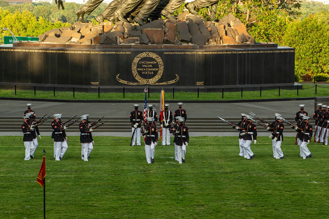 Marines with the Silent Drill Platoon perform during the Tuesday Sunset Parade at the Marine Corps War Memorial, Arlington, Va., July 13, 2021. The hosting official for the evening was Brig. Gen. George B. Rowell IV, Director of Communication, Headquarters, Marine Corps, and the guest of honor was Vice Admiral Sean Buck, Superintendent of the United States Naval Academy. (U.S. Marine Corps photo by Lance Cpl. Allen Sanders)