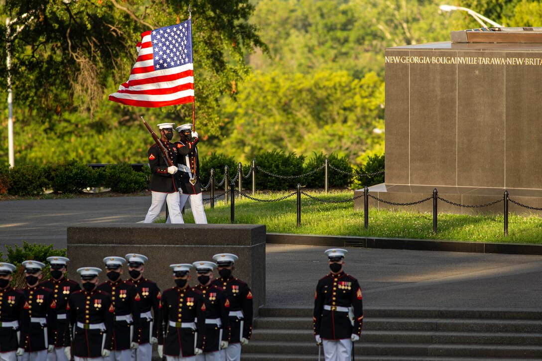 Marines with the Official U.S. Marine Corps Color Guard march into formation during the Tuesday Sunset Parade at the Marine Corps War Memorial, Arlington, Va., July 13, 2021. The hosting official for the evening was Brig. Gen. George B. Rowell IV, Director of Communication, Headquarters, Marine Corps, and the guest of honor was Vice Admiral Sean Buck, Superintendent of the United States Naval Academy. (U.S. Marine Corps photo by Lance Cpl. Tanner D. Lambert)