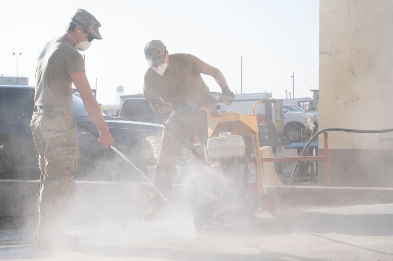 Senior Airman Garrett Cothran, left, and Airman 1st Class Christian Atkins, right, 341st Civil Engineer Squadron heavy equipment operators, make relief cuts into new concrete July 14, 2021, at Malmstrom Air Force Base, Mont.