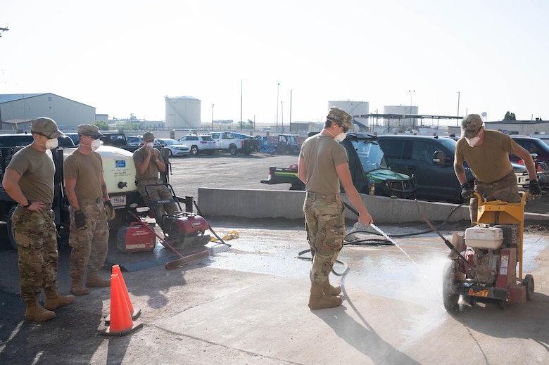 Senior Airman Garrett Cothran, center, and Airman 1st Class Christian Atkins, right, 341st Civil Engineer Squadron heavy equipment operators, make relief cuts into new concrete while other members of the team wait to assist July 14, 2021 at Malmstrom Air Force Base, Mont.