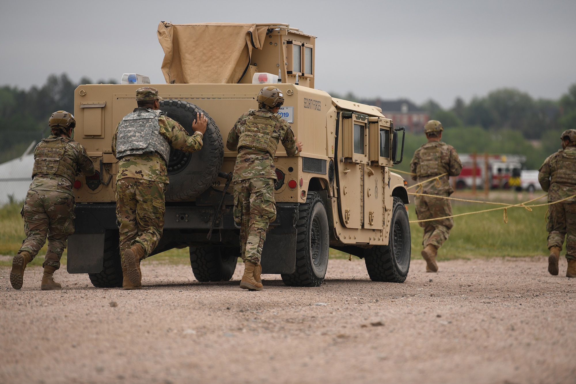A group of Airmen push a High Mobility Multipurpose Wheeled Vehicle (HMMWV) during the 90th Civil Engineering Squadron Readiness Challenge on F.E. Warren Air Force Base, Wyoming, July 1, 2021. The purpose of the exercise was to train the readiness capabilities of the Airmen with the 90 CES. (U.S. Air Force photo by Airman 1st Class Darius Frazier)