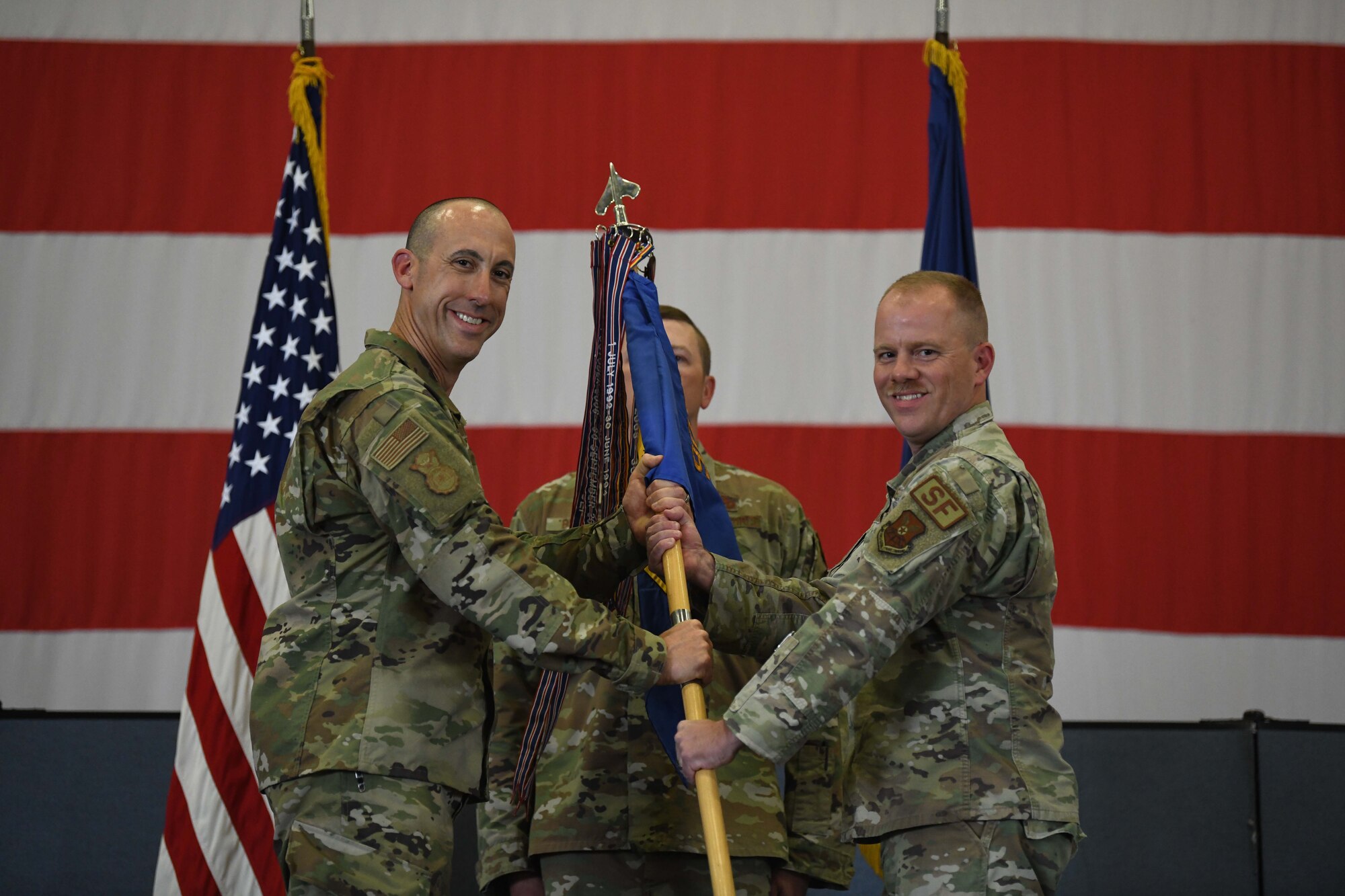 Col. Damian Schlussel, commander of the 90th Security Forces Group and Lt. Col. William Brokaw, incoming commander of the 90th Missile Security Forces Squadron, pose for a photo while passing the guidon during the 90 MSFS change of command ceremony in the Peacekeeper High Bay on F.E. Warren Air Force Base, Wyoming, July 13, 2021. The ceremony is to signify the transition of authority from Lt. Col David Celeste, outgoing commander of the 90th Missile Security Forces Squadron, to Brokaw. (U.S. Air Force photo by Airman 1st Class Darius Frazier)