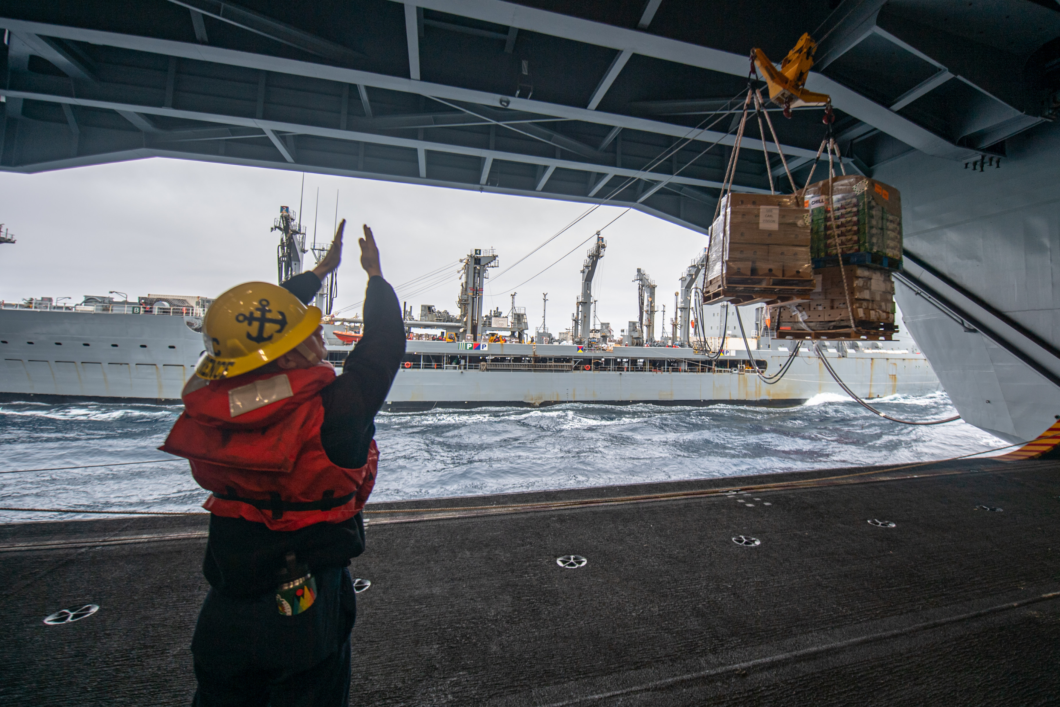 Boatswain’s Mate 3rd Class Nicholas Lawrence, a native of Waukesha, Wisconsin, guides a cargo onload aboard the Nimitz-class aircraft carrier USS Carl Vinson (CVN 70).