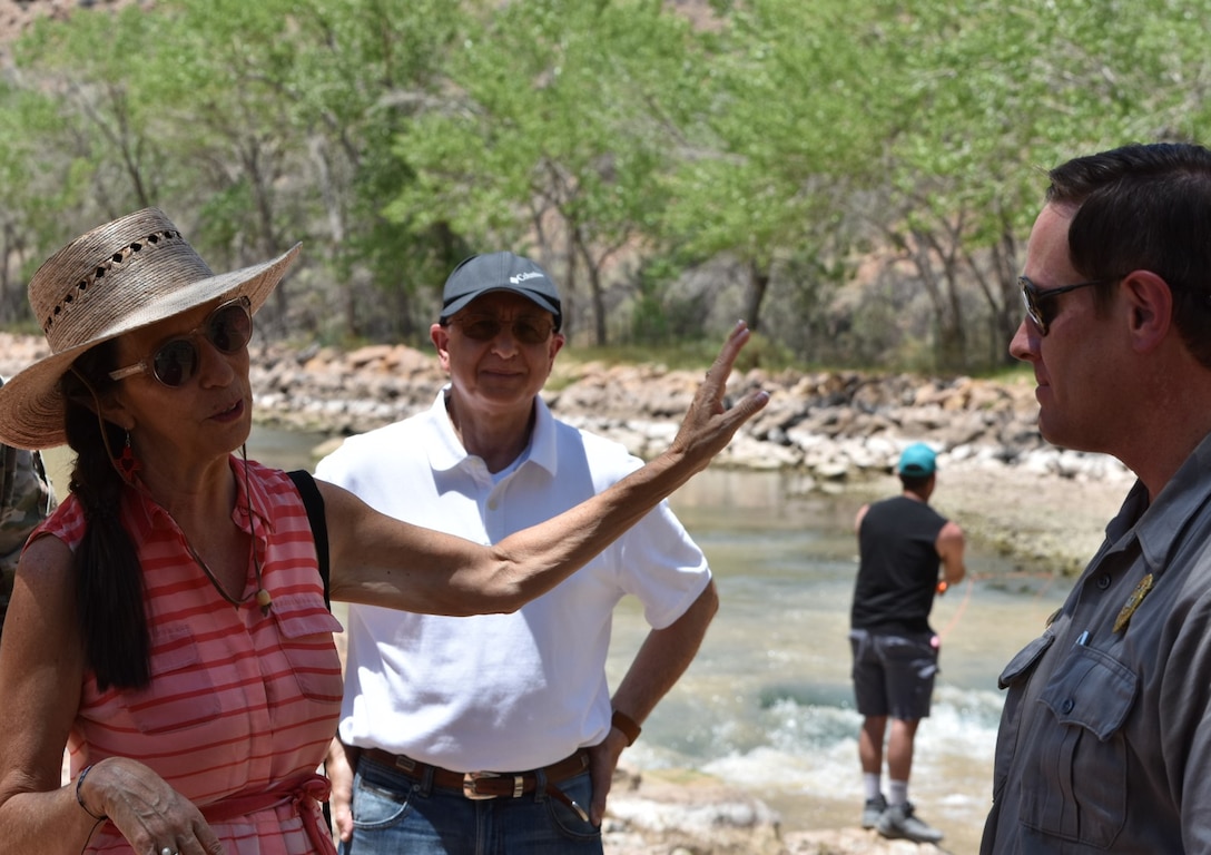 Congresswoman Teresa Leger Fernández (left) discusses the Rio Chama Habitat Improvement project with Nabil Shafike, chief water management (center) and John Mueller, lake operations manager, Abiquiu Lake, during her visit to Abiquiu Lake and Dam, July 10, 2021. In the background a fisherman practices his fly-fishing.