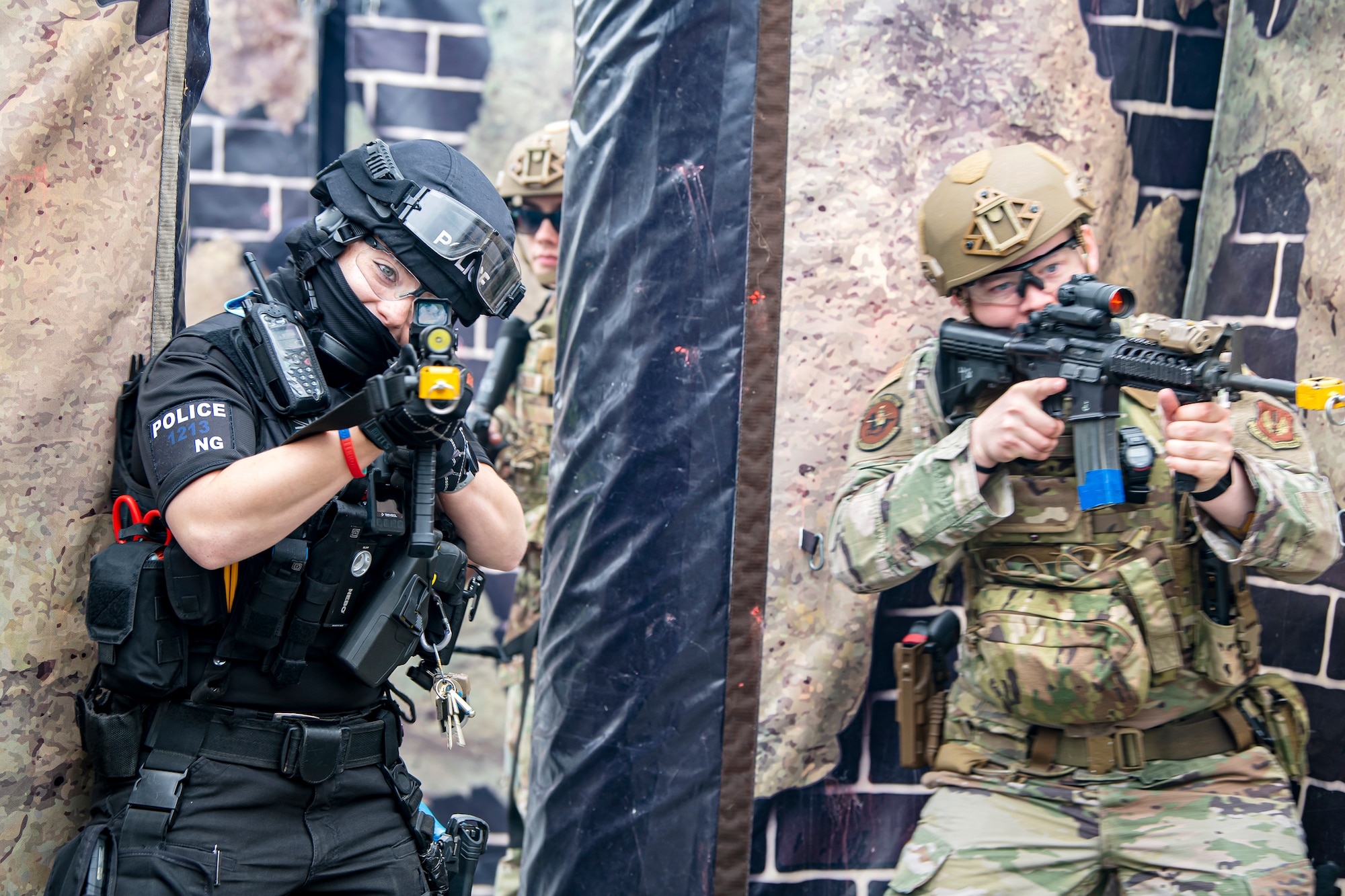 An Airman from the 422nd Security Forces Squadron, along with a police officer from the Northamptonshire police department, defend their position during a tri-agency active shooter response exercise at RAF Croughton, England, June 30, 2021. Airmen from the 422nd SFS along with police officers from the NHPD and Ministry of Defense, participated in multiple exercises to enhance their search and seizure tactics, strengthen local ties and gain rapport with their fellow officers. (U.S. Air Force photo by Senior Airman Eugene Oliver)