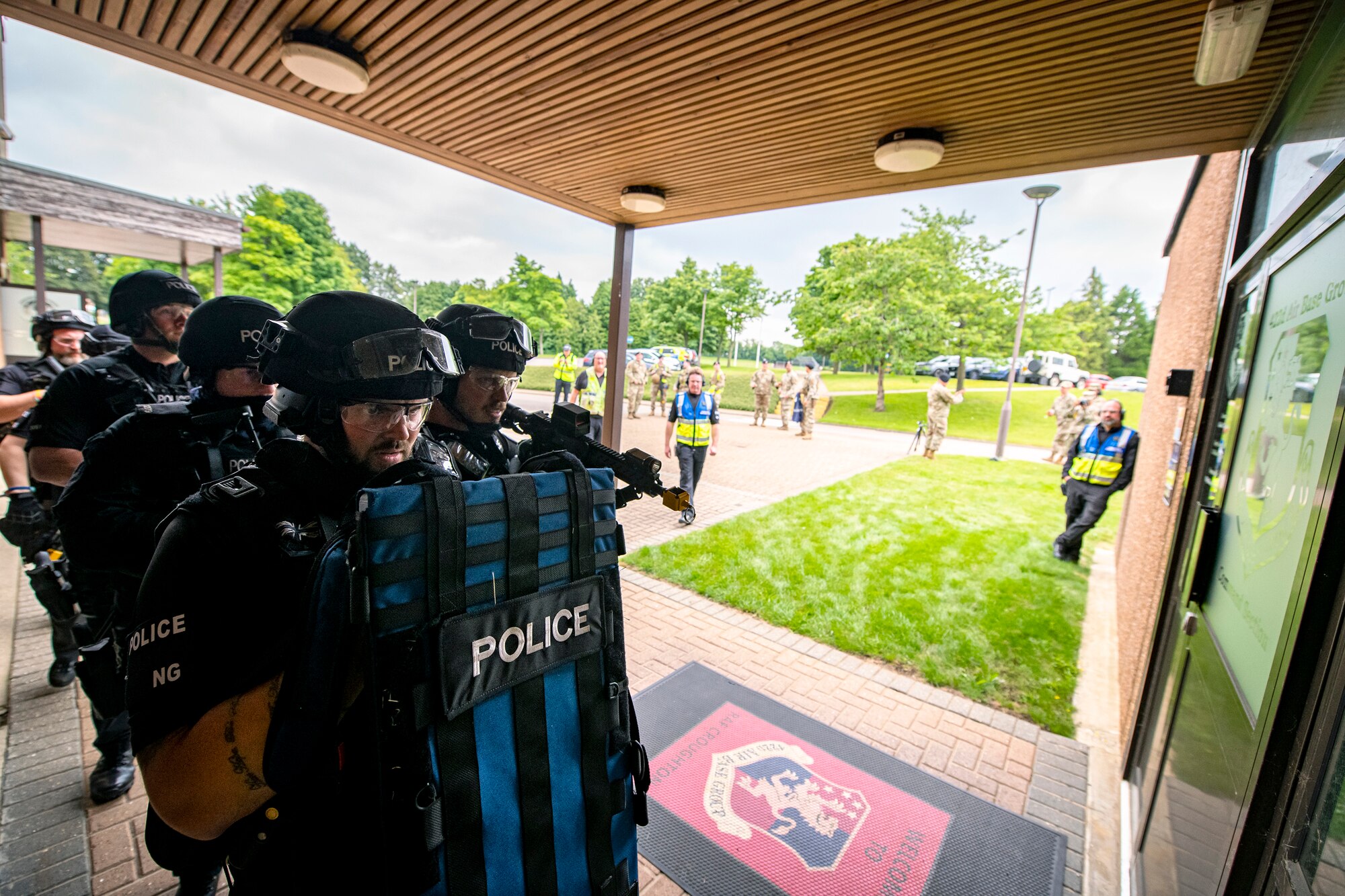 Police Officers from the Northamptonshire police department, prepare to enter a building during a tri-agency active shooter response exercise at RAF Croughton, England, June 30, 2021. Airmen from the 422nd Security Forces Squadron along with police officers from the NHPD and Ministry of Defense, participated in multiple exercises to enhance their search and seizure tactics, strengthen local ties and gain rapport with their fellow officers. (U.S. Air Force photo by Senior Airman Eugene Oliver)