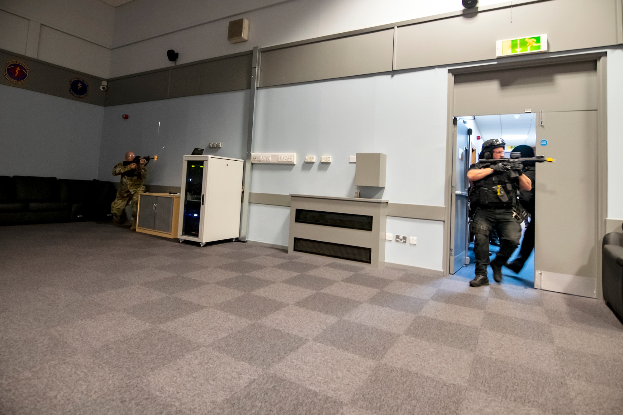 A simulated active shooter, left, engages with police officers from the Northamptonshire police department, during a tri-agency active shooter response exercise at RAF Croughton, England, June 30, 2021. Airmen from the 422nd Security Forces Squadron along with police officers from the NHPD and Ministry of Defense, participated in multiple exercises to enhance their search and seizure tactics, strengthen local ties and gain rapport with their fellow officers. (U.S. Air Force photo by Senior Airman Eugene Oliver)