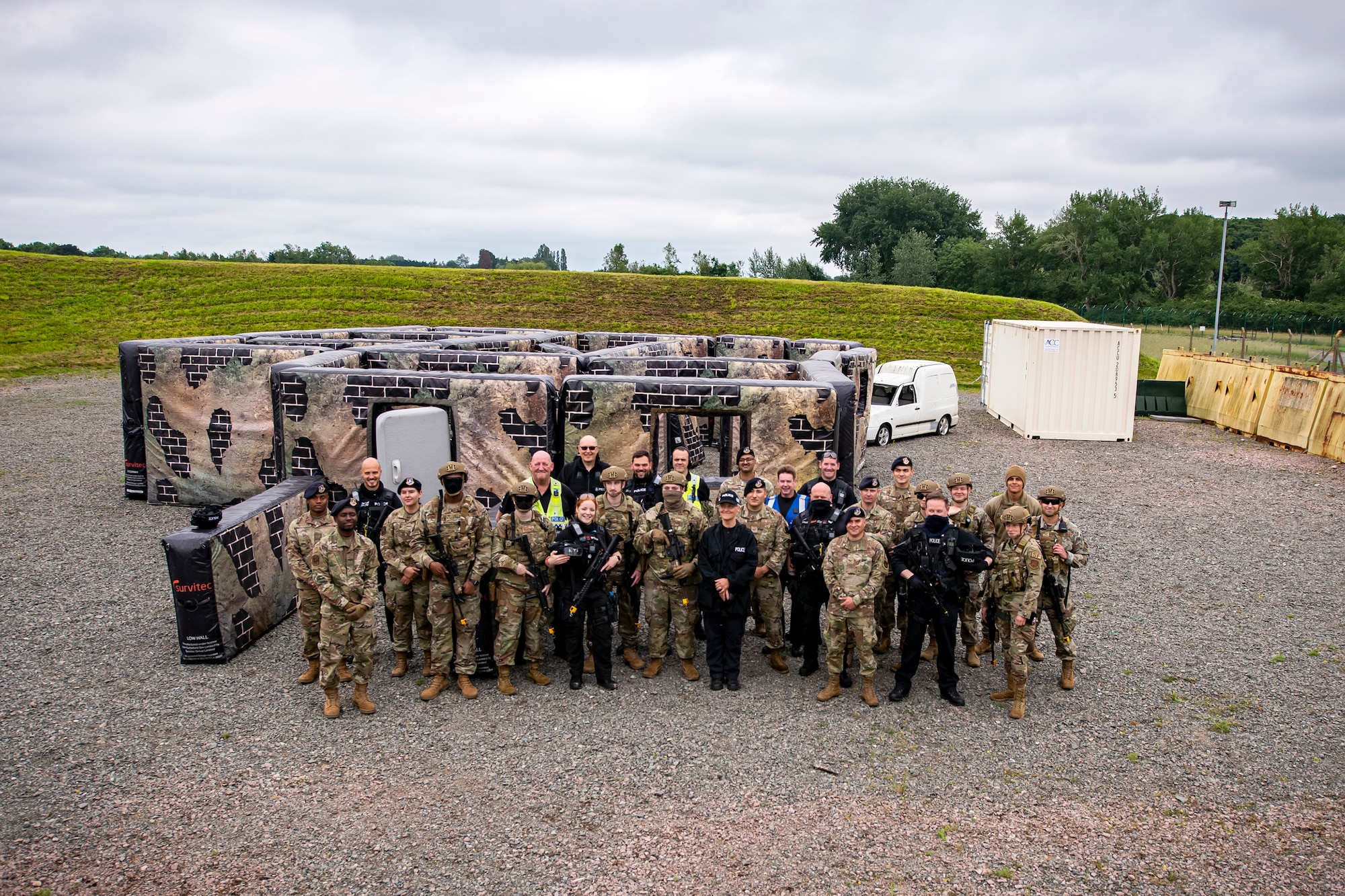 Police Officers from the Northamptonshire Police Department, Ministry of Defense, and Airmen from the 422nd Security Forces Squadron, pose for a group photo during a tri-agency active shooter response exercise at RAF Croughton, England, June 30, 2021. Airmen from the 422nd SFS along with police officers from the NHPD and Ministry of Defense, participated in multiple exercises to enhance their search and seizure tactics, strengthen local ties and gain rapport with their fellow officers. (U.S. Air Force photo by Senior Airman Eugene Oliver)