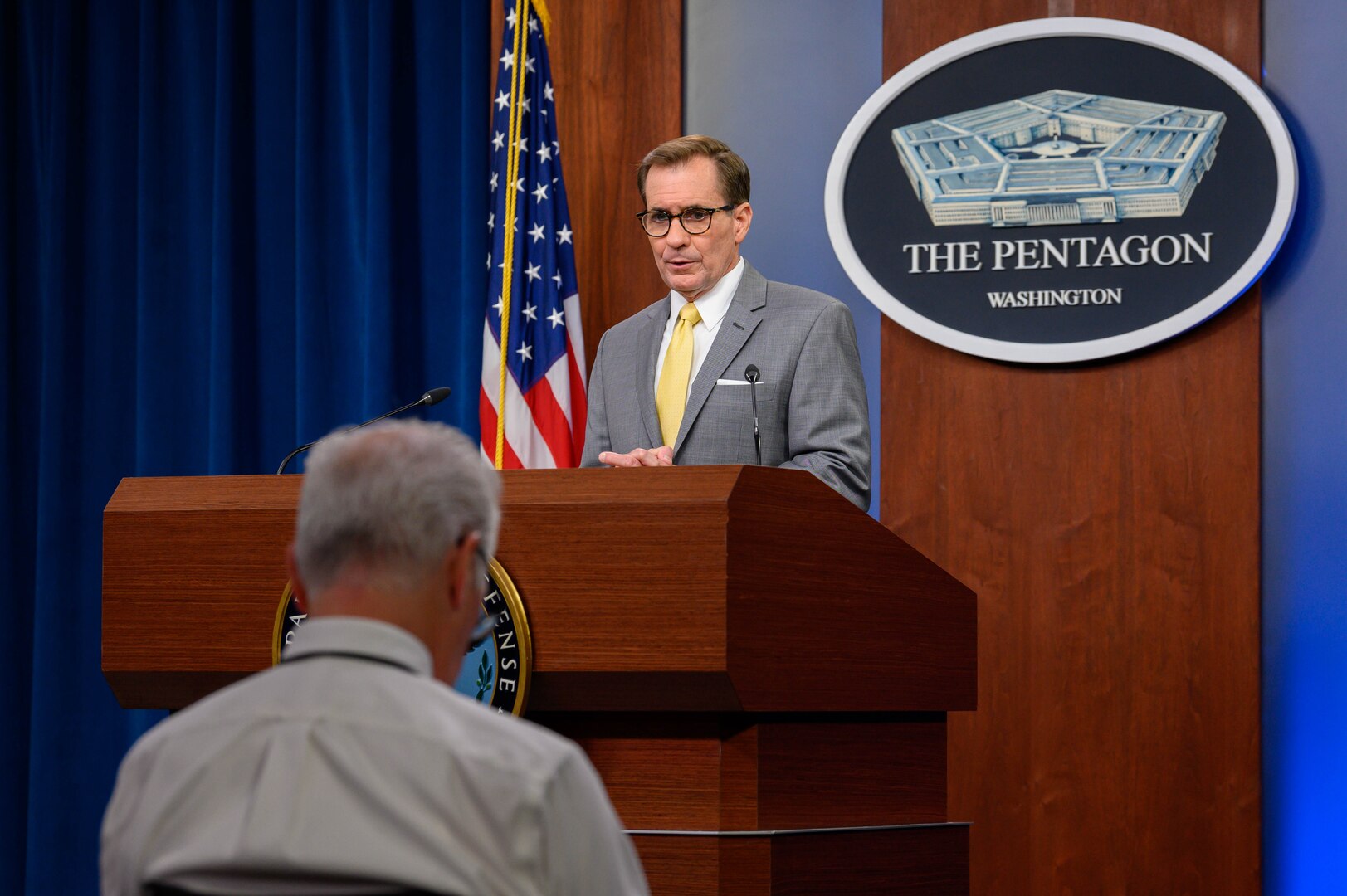 A man stands behind a lectern. Behind him is a sign that reads "The Pentagon."