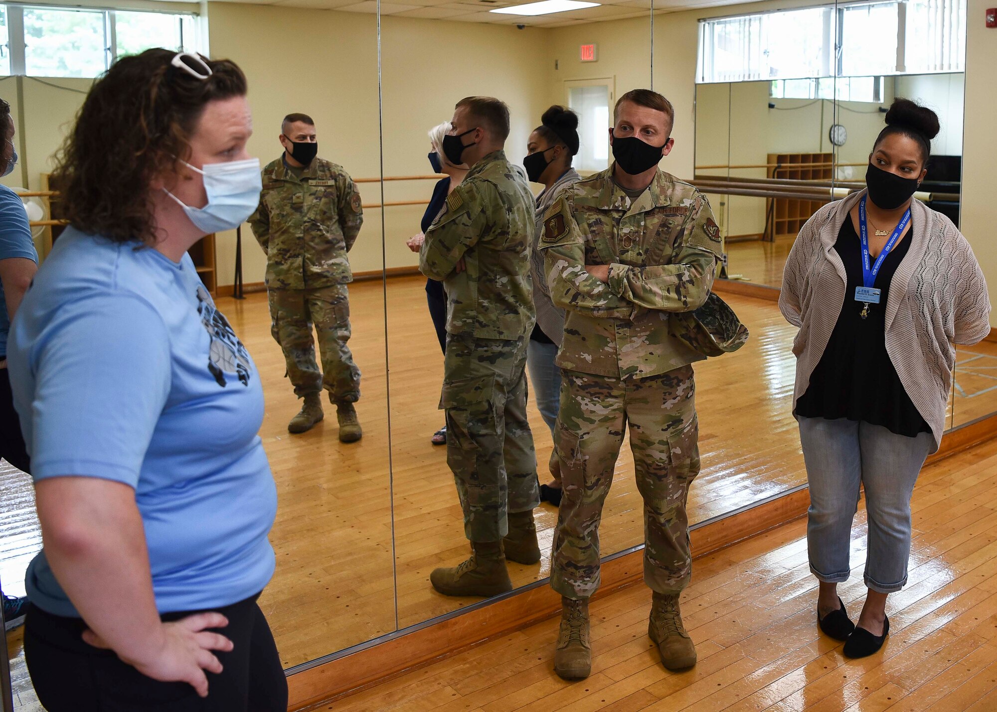 Military members talk to Lunney Youth Center staff members in a dance room.