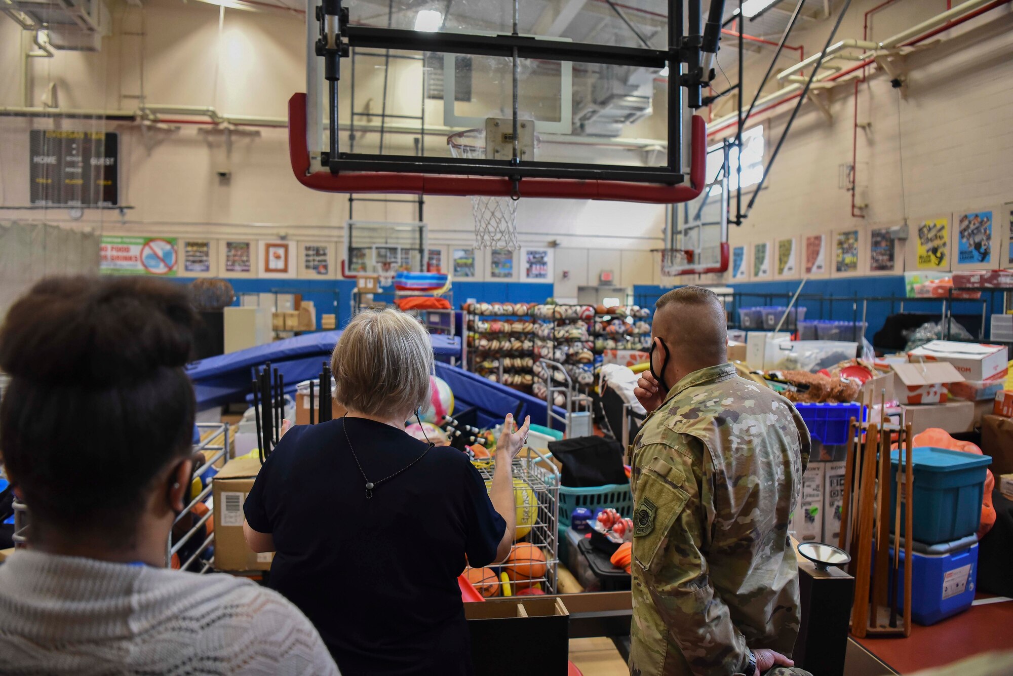 A military member and a Lunney Youth Center staff member look at the equipment the center has in a gym.