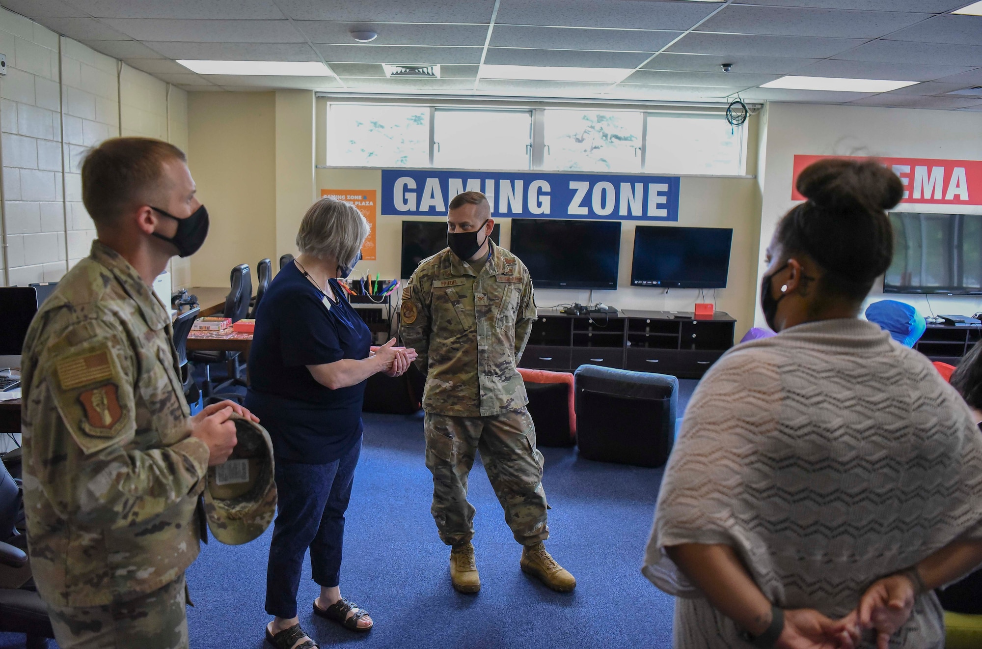 Two military members talk to Lunney Youth Center staff members in the entertainment room.