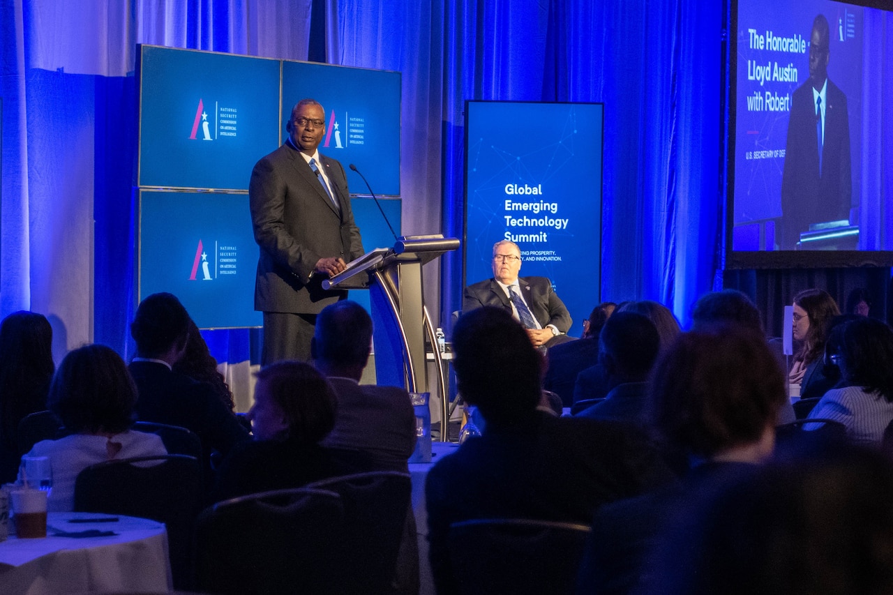 A man stands on a stage and speaks at a podium in front of a room of people.