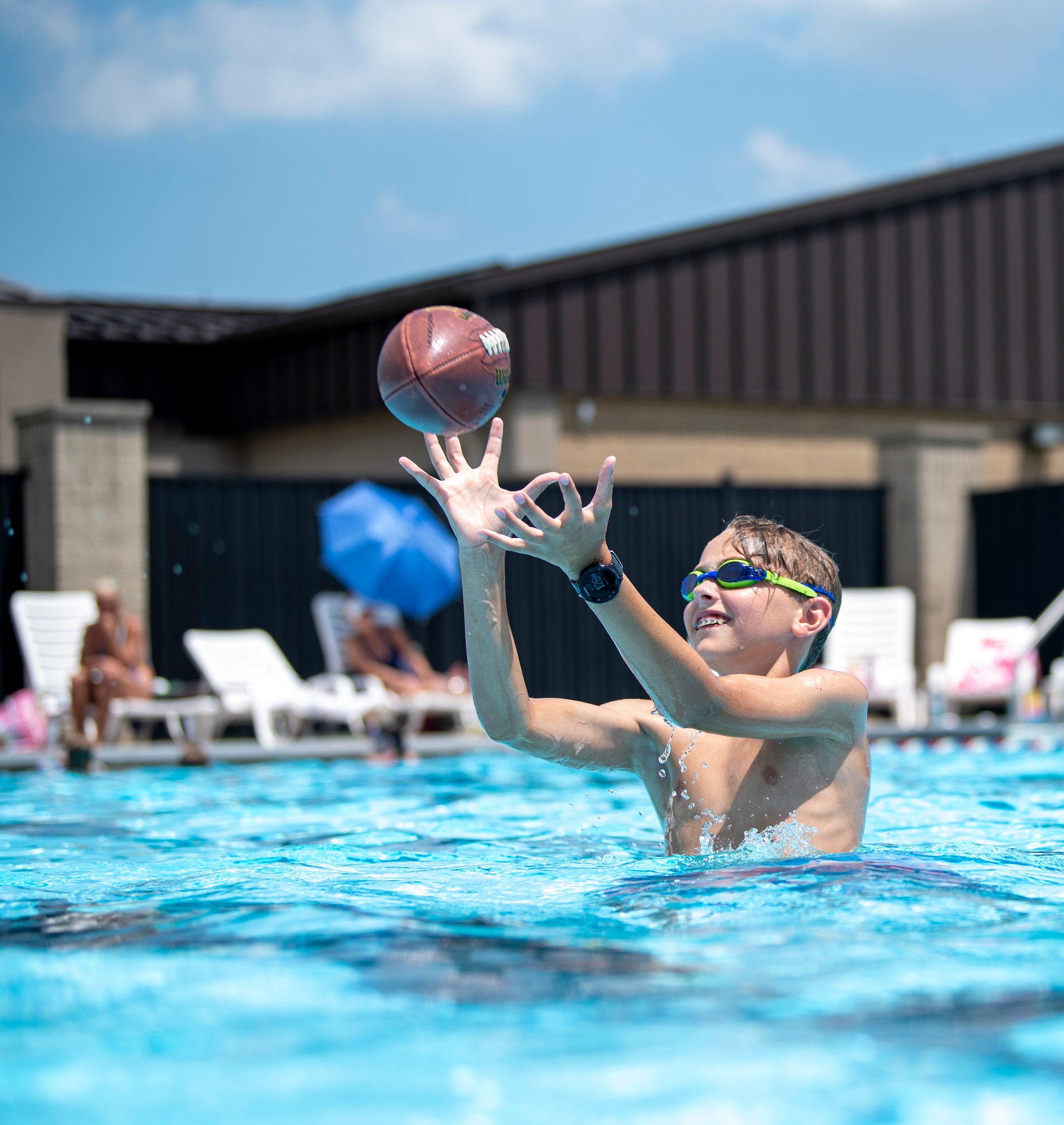Parker Evans, son of Tech. Sgt. Jason Evans, 436th Civil Engineer Squadron explosive ordnance disposal, catches a football at the Oasis Pool at Dover Air Force Base, Del., July 14, 2021. During summer break, the pool is open 11 am to 7 pm daily for military members, family and friends. The pool no longer has block sessions for attendees, but has a capacity limit of 200 people.  (U.S. Air Force photo by Tech. Sgt. Nicole Leidholm)