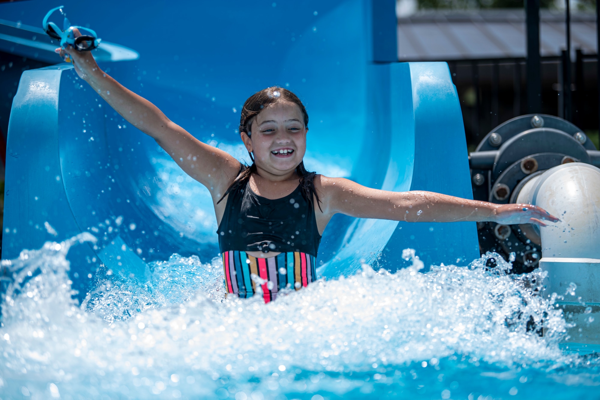 A girl slides down the waterslide at the Oasis Pool at Dover Air Force Base, Del., July 14, 2021. During summer break, the pool is open 11 am to 7 pm daily for military members, family and friends. The pool no longer has block sessions for attendees, but has a capacity limit of 200 people.  (U.S. Air Force photo by Tech. Sgt. Nicole Leidholm)