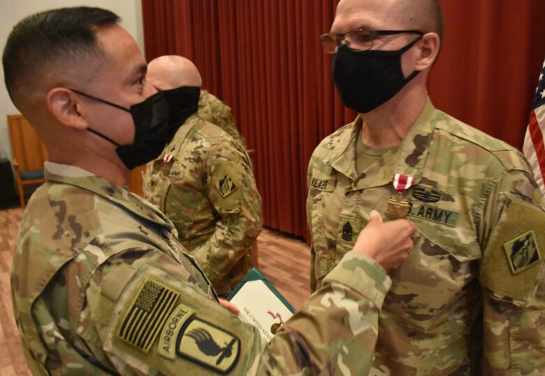 Command Sergeant Major Delfin Romani, Transatlantic Division CSM pins the Meritorious Service Medal on the lapels of Task Force Essayons outgoing Commander, Colonel John Haas, Jr. and outgoing Senior Enlisted Advisor, Sergeant Major William Klaers during the awards ceremony held within the Casing/Uncasing ceremony held at Camp Arifjan, Kuwait on May 15, 2021. (Photo by Rick Benoit)