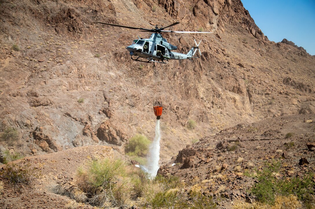 A U.S. Marine Corps UH-1Y Venom with Marine Operational Test and Evaluation Squadron (VMX) 1, dumps water into a watering hole near the Chocolate Mountain Aerial Gunnery Range, Calif., July 7, 2021.