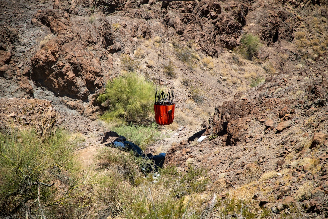 A U.S. Marine Corps UH-1Y Venom with Marine Operational Test and Evaluation Squadron (VMX) 1, dumps water into a watering hole near the Chocolate Mountain Aerial Gunnery Range, Calif., July 7, 2021. Man-made watering holes help animals in the desert access water easily all year round. (U.S. Marine Corps photo by Lance Cpl Gabrielle Sanders)