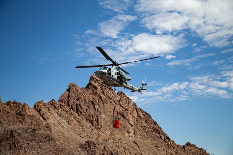 A U.S. Marine Corps UH-1Y Venom with Marine Operational Test and Evaluation Squadron (VMX) 1, dumps water into a watering hole near the Chocolate Mountain Aerial Gunnery Range, Calif., July 7, 2021. Man-made watering holes help animals in the desert access water easily all year round. (U.S. Marine Corps photo by Lance Cpl Gabrielle Sanders)