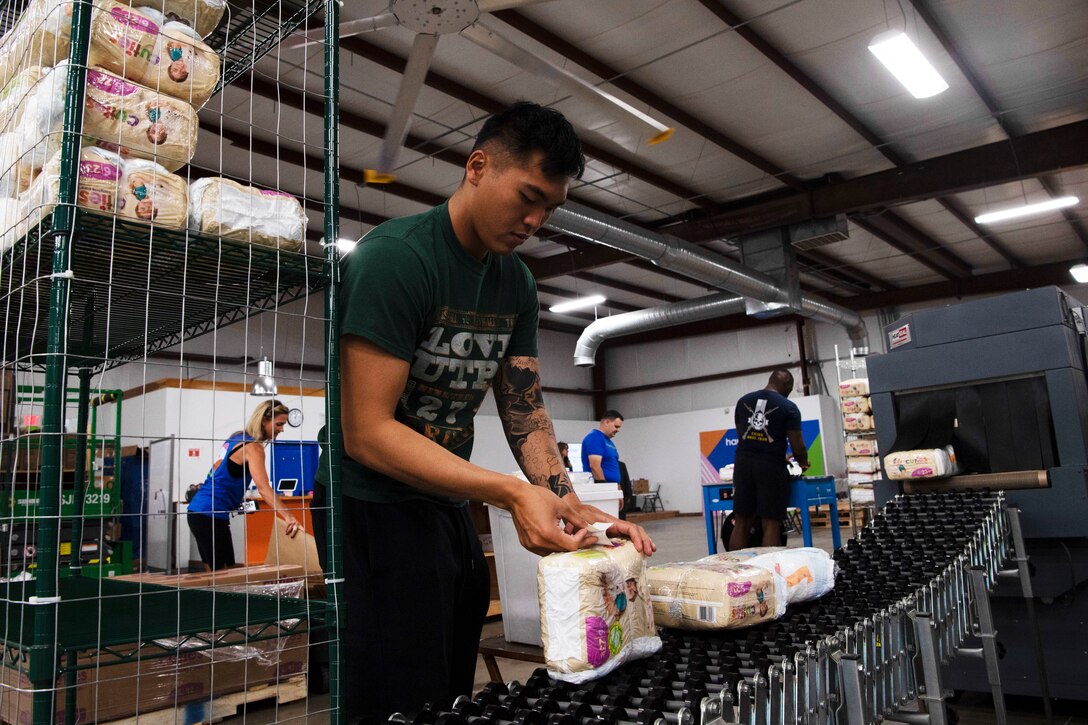 A sailor packages diapers during a community event.