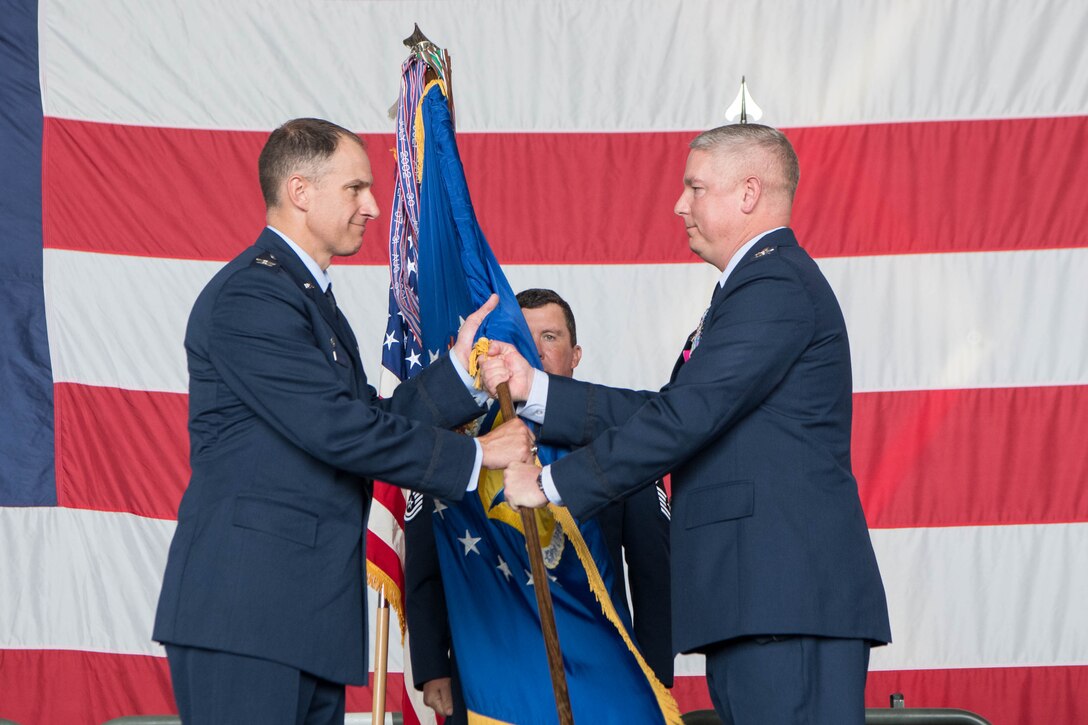 Col. Matthew Husemann, left, 436th Airlift Wing commander passes the guidon to Col. Scott Raleigh, incoming 436th Operations Group commander, during a change of command ceremony at Dover Air Force Base, Delaware, July 15, 2021. The ceremony saw Peeler relinquish command to Col. Scott Raleigh. The 436th OG operates Dover AFB’s fleet of C-5M Super Galaxy and C-17 Globemaster III aircraft supporting rapid global mobility. (U.S. Air Force photo by Mauricio Campino)
