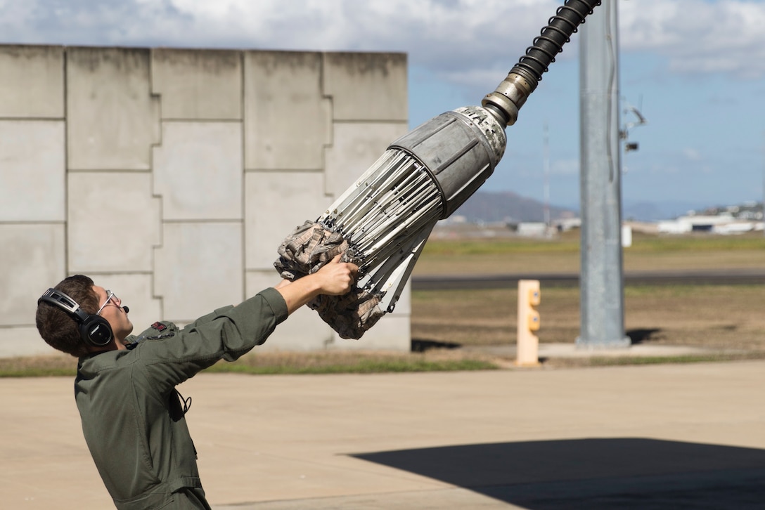 A Marine pulls on the refueling nozzle on an aircraft.