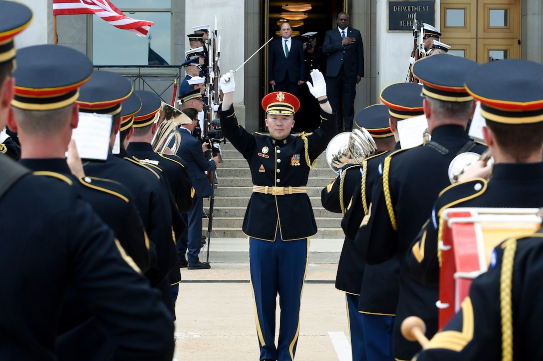 A band performs at the steps of the Pentagon while Defense leaders observe.