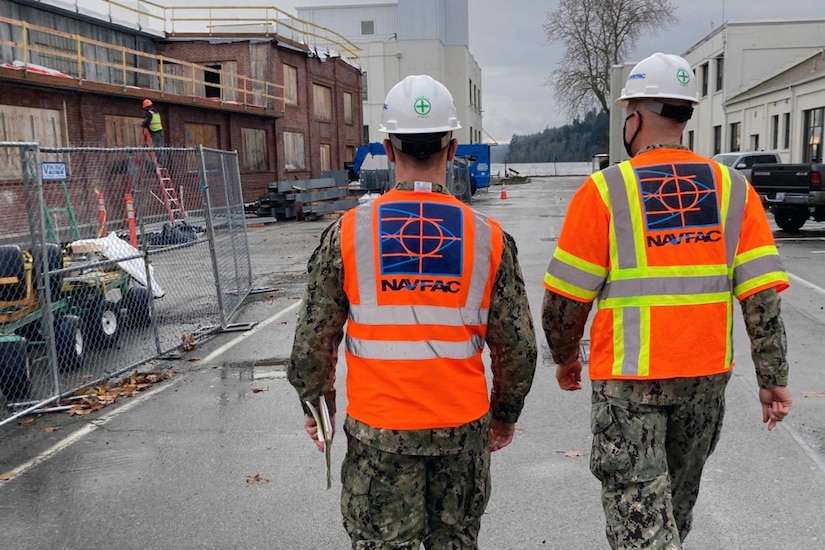 Two officers tour a Navy construction project.