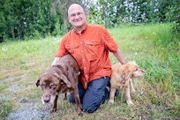 Retired Col. Jeff Arnold, force integration readiness officer for the Alaska Army National Guard, poses with his dogs Luna and Copper, July 7, 2021 on Joint Base Elmendorf-Richardson. Arnold retired from the Alaska Army National Guard in May after 40 years of service, but continues to work as a federal civilian for the organization. (U.S. Army National Guard photo by Edward Eagerton)