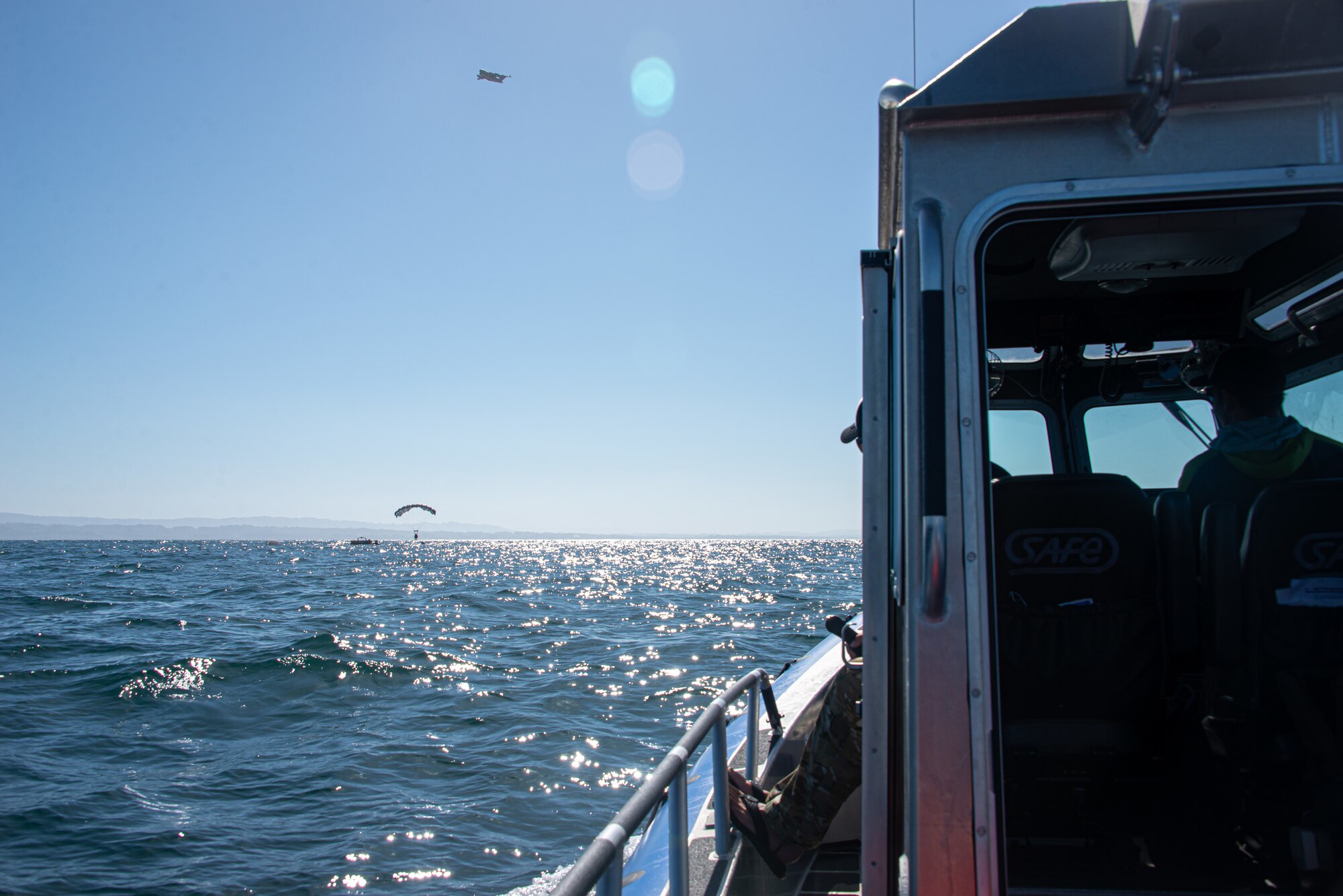 Guardian Angel pararescuemen from the 131st Rescue Squadron parachute descend into the ocean May 20, 2021, at Santa Cruz Water Drop Zone, Calif. Airmen, rescue craft and life-support equipment were airdropped by a C-17 Globemaster III, operated by a Hawaii Air National Guard aircrew.