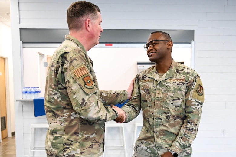 Senior Airman Spain and Lt. Gen. Kirkland shake hands.