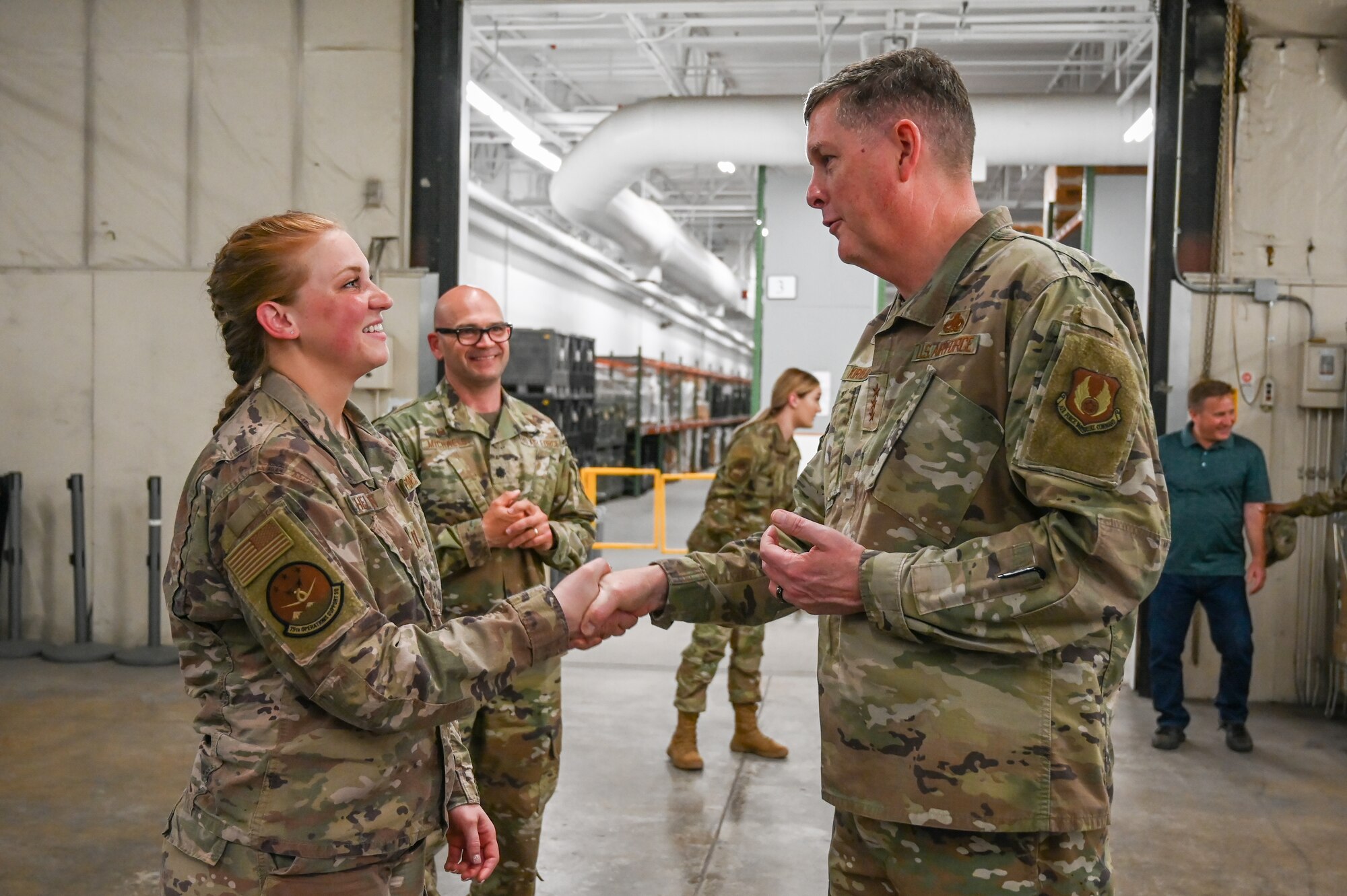 Capt. Shelton shakes hands with Lt. Gen. Kirland while other Airmen look on in the background.